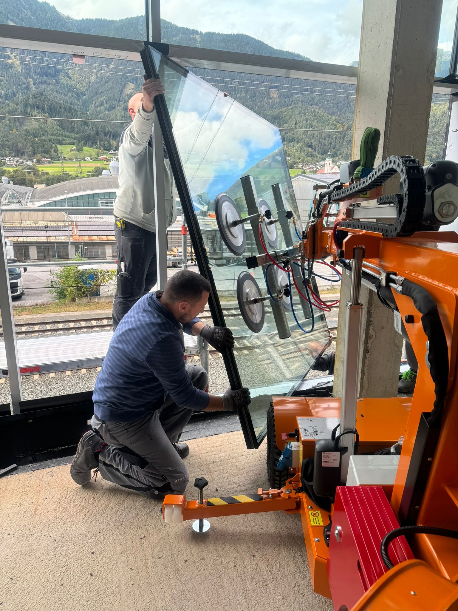 Glasmontage: Arbeiter setzt große Glasscheibe mit Sauganlage ein.